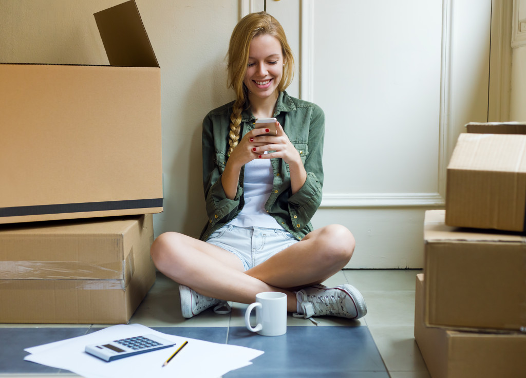 Portrait of young beautiful woman with mobile phone in her new house.