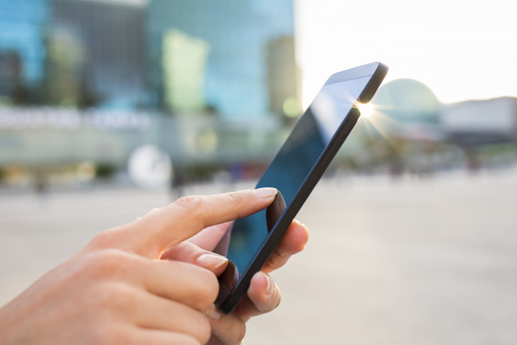 Businesswoman sending messages with her mobile phone, building Background