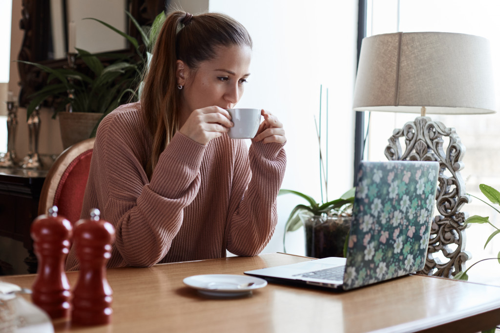 Woman looking at her laptop while drinking coffee