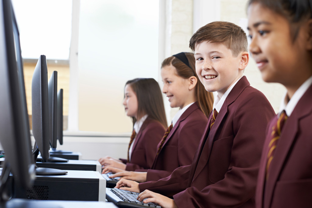 Students in uniforms using computers in school