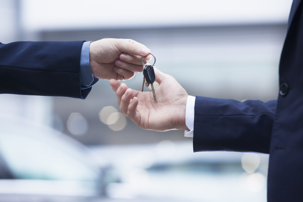 Car salesman handing over the keys for a new car to a young businessman