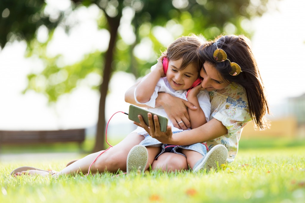 woman hugging her child watching on smart phone