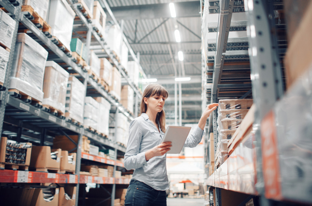 female worker checking packages in a metal shelf in a warehouse