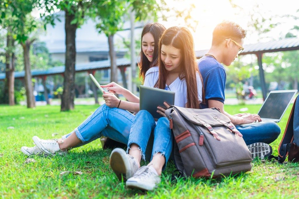 students sitting and studying on the grass of campus