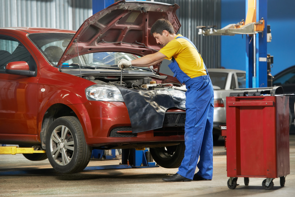 One young auto mechanic tighten screw with spanner during automobile car maintenance at engine auto repair shop service station