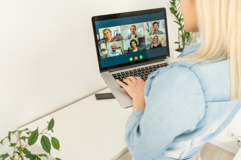 Back view of business woman talking to her colleagues about plan in video conference. Multiethnic business team using laptop for a online meeting in video call. Group of people smart working from home