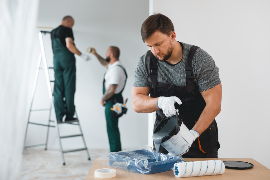 Three efficient renovation crew painting white walls of new build home