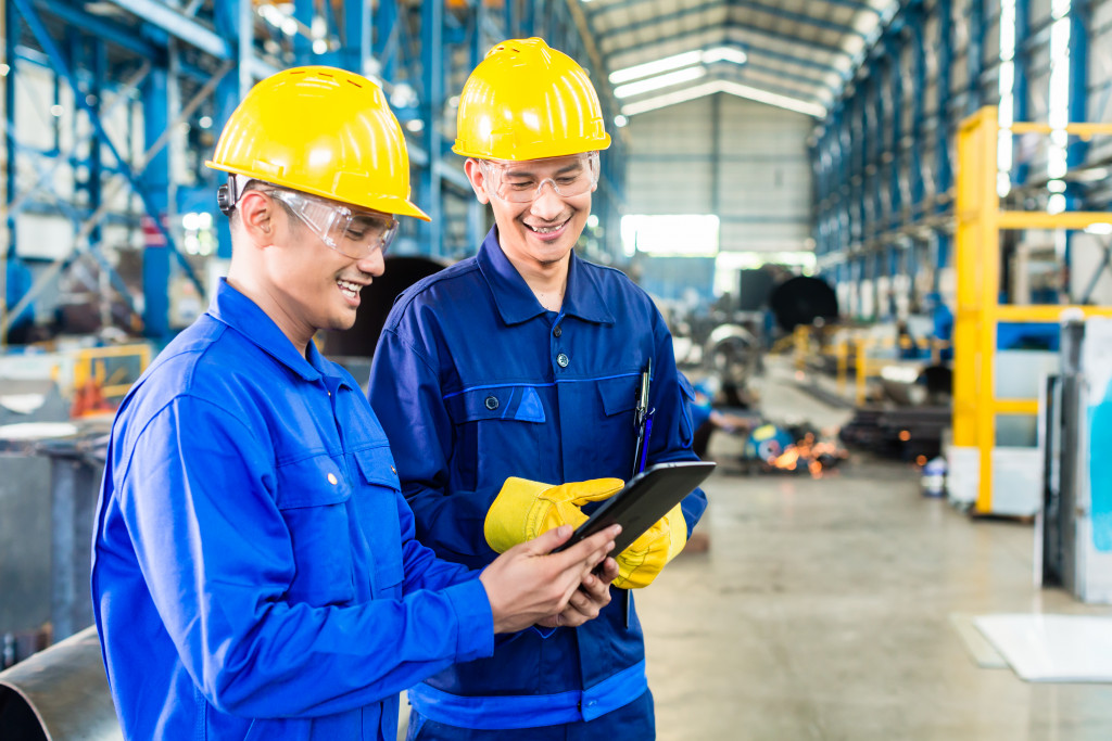 Two workers in production plant as team discussing, industrial scene in background