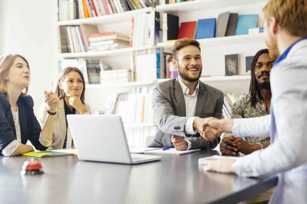 group of business professionals on a meeting with two men shaking hands