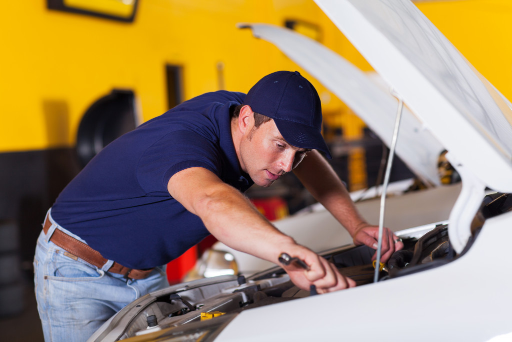 auto mechanic repairing vehicle inside workshop