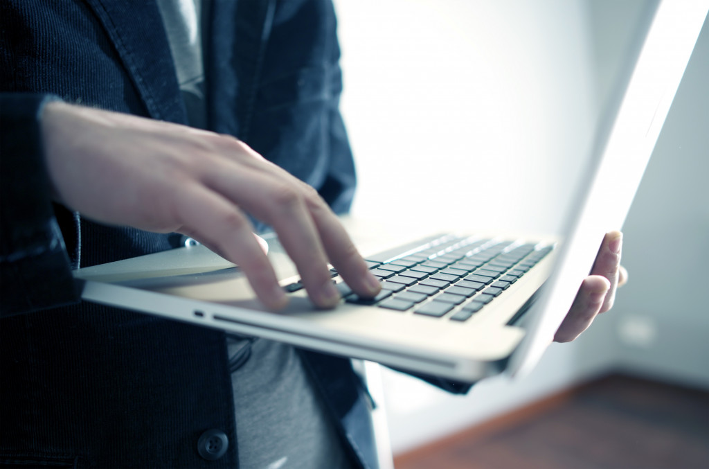 Male Businessman Working While Standing on the Laptop in Office Area.