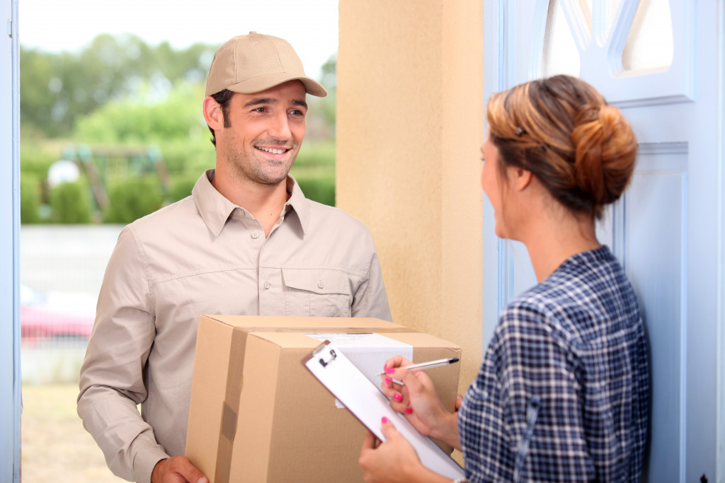 a courier on a doorstep carrying a box delivery