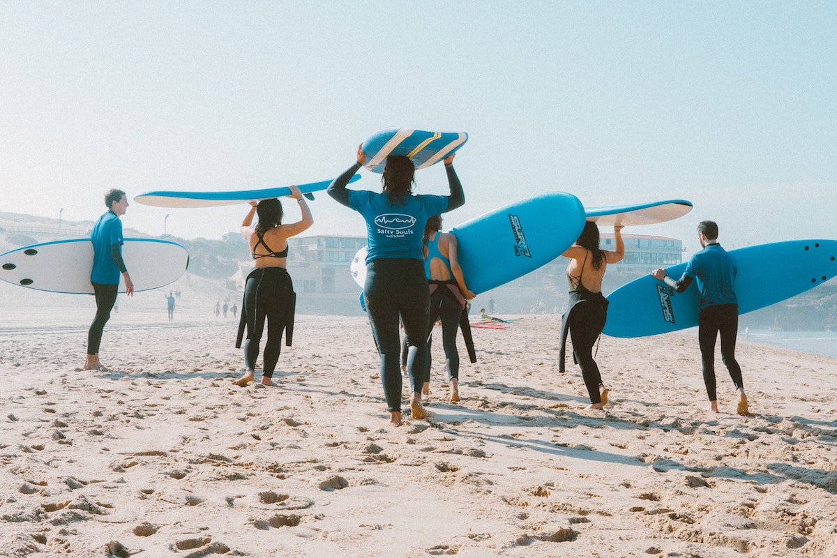 group-of-people-carrying-surfboards