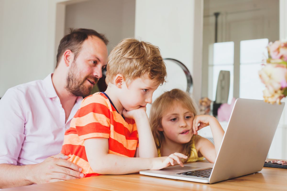 man letting kids use his laptop